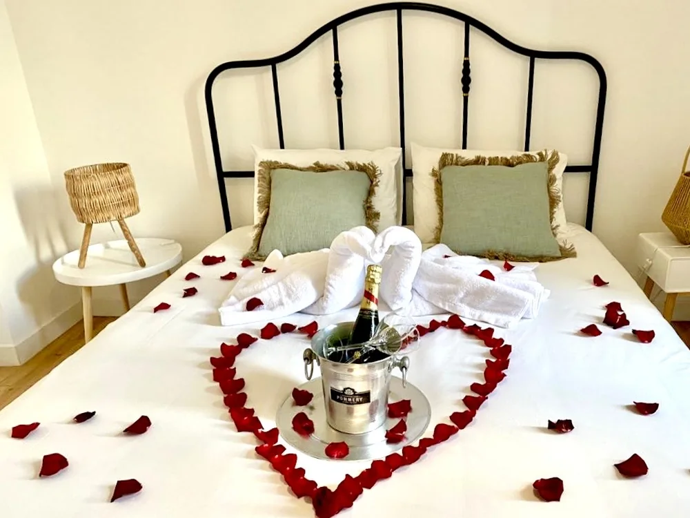 Décoration romantique : cœur de pétales de roses sur le lit et champagne